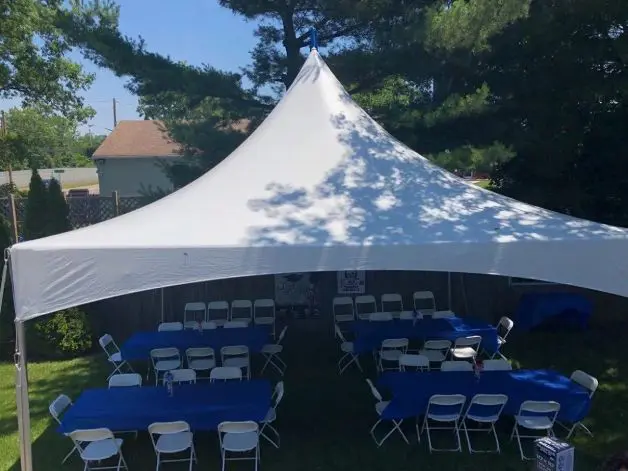 A large white tent with tables and chairs in front of it.