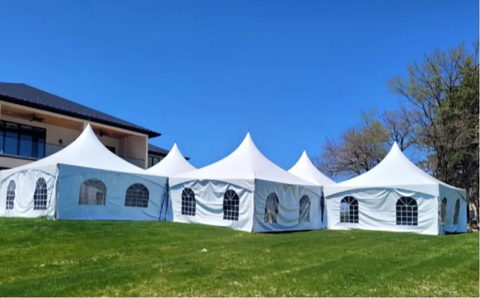 A group of tents in the grass near a building.