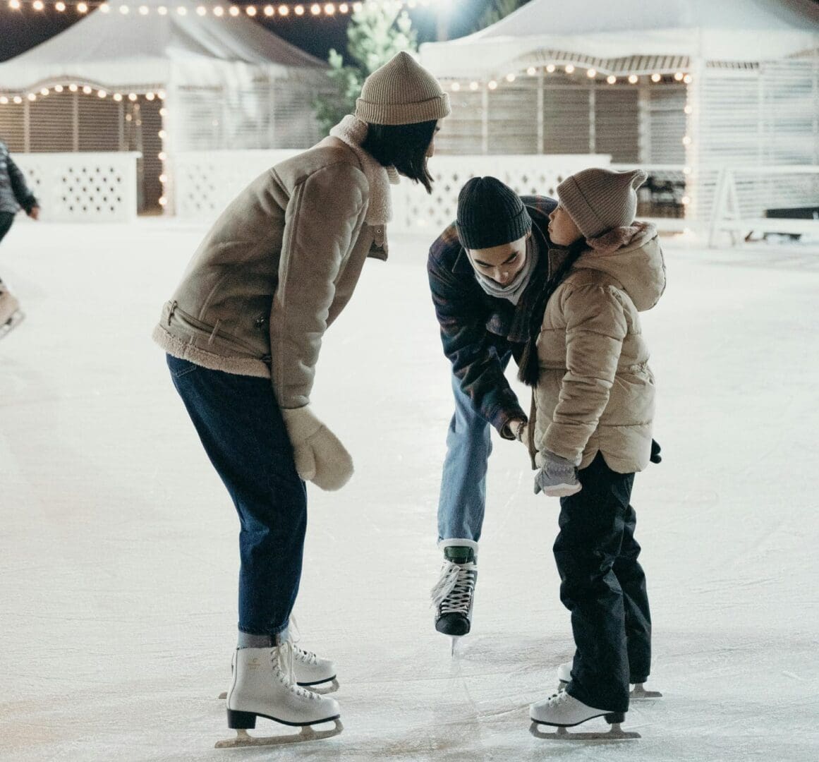 Three people on ice skates in a rink.